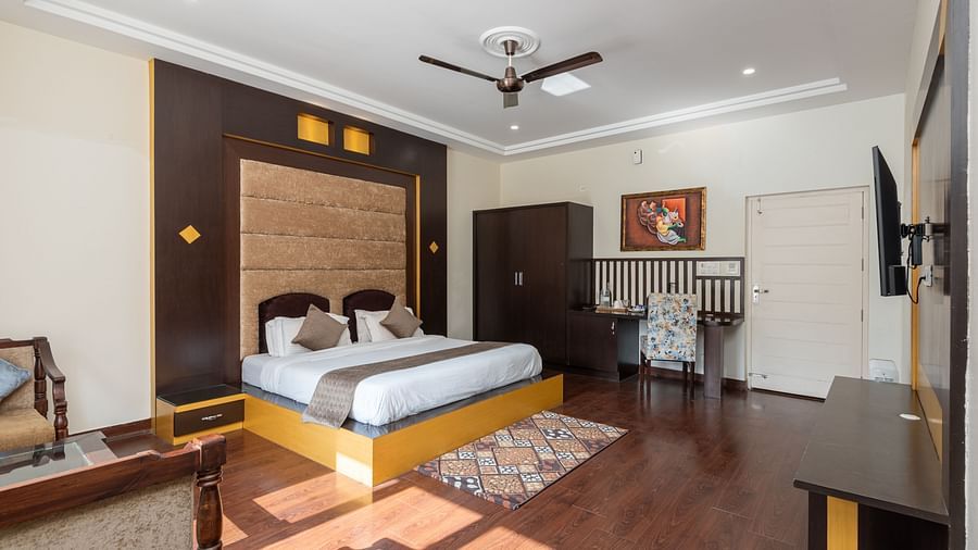 Spacious and well-lit guest room at DLS Tehri Club Resort with a king size bed and a work desk.